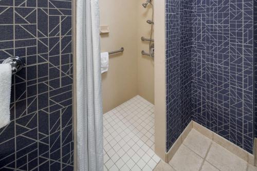 a bathroom with a shower with blue tiles at Homewood Suites by Hilton Newburgh-Stewart Airport in New Windsor