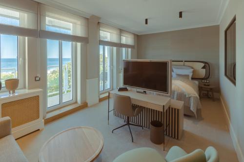 Schlafzimmer mit einem Schreibtisch, einem TV und einem Bett in der Unterkunft Strandhotel Ostende in Ahlbeck