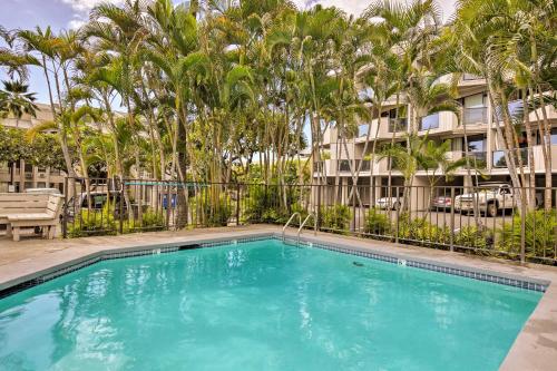 a swimming pool with palm trees and a building at Downtown Kailua-Kona Condo with Pool and Views in Kailua-Kona
