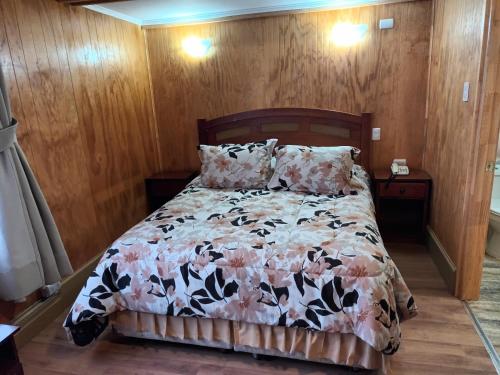 a bedroom with a bed with a floral comforter at HOTEL CASAGRANDE con estacionamiento EXCLUSIVO in Valdivia