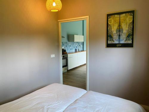 a bedroom with a white bed and a kitchen at Gastenverblijf in rustige groene omgeving - Kievit Leuvenheim in Leuvenheim