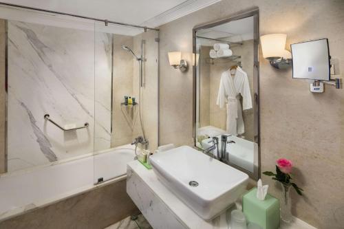 a white bathroom with a sink and a shower at Hilton Alexandria Corniche Hotel in Alexandria