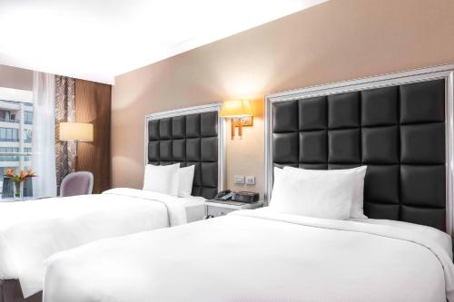 two beds in a hotel room with white sheets at Hilton Alexandria Corniche Hotel in Alexandria