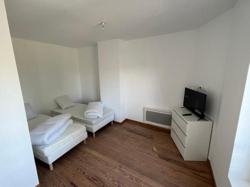Habitación blanca pequeña con 2 camas y TV en Chez Tiago, en Nesle