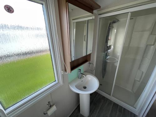 La salle de bains est pourvue d'un lavabo et d'une douche. dans l'établissement 8 Berth Static Caravan - Holiday Resort Unity Brean, à Berrow