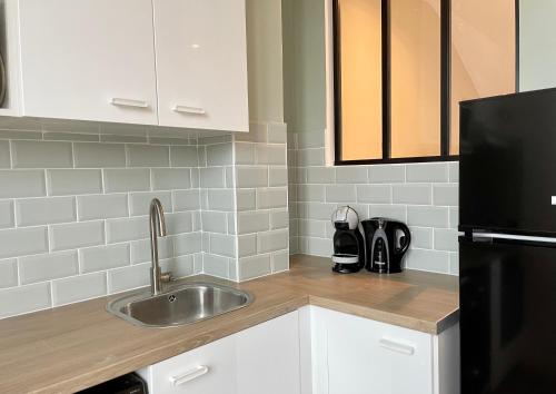 a kitchen with a sink and a black refrigerator at Le Cocon - logement 4 personnes - Neuf - Wifi in Le Bourget