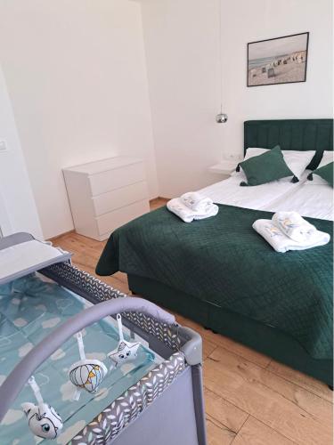 a bedroom with a green bed with towels on it at SOLEK Apartamenty i pokoje gościnne in Mielno