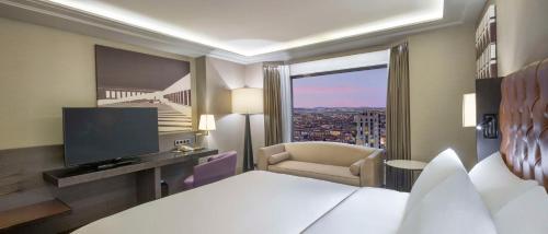 a bedroom with a bed and a tv and a chair at Ankara HiltonSA in Ankara