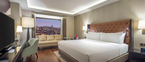 a bedroom with a large white bed and a window at Ankara HiltonSA in Ankara