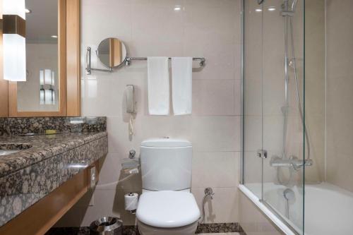 a bathroom with a toilet and a shower and a phone at Ankara HiltonSA in Ankara
