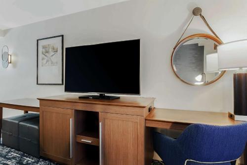 a hotel room with a tv and a desk with a blue chair at Hampton Inn & Suites Austin - Downtown in Austin