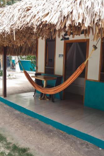 a hammock in front of a thatch hut at Isla Grande Eco-Hostal in Isla Grande
