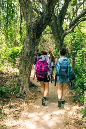 a group of people walking down a trail with backpacks at Isla Grande Eco-Hostal in Isla Grande