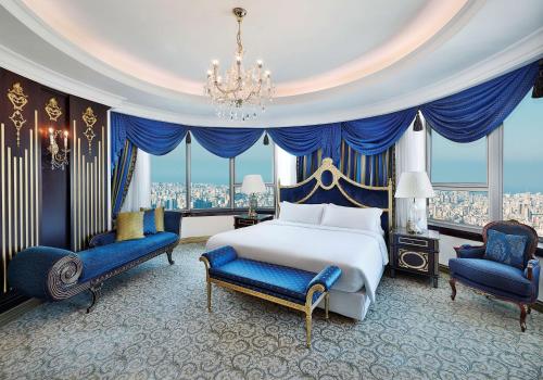 a bedroom with a bed and two chairs and a chandelier at Hilton Beirut Habtoor Grand Hotel in Beirut