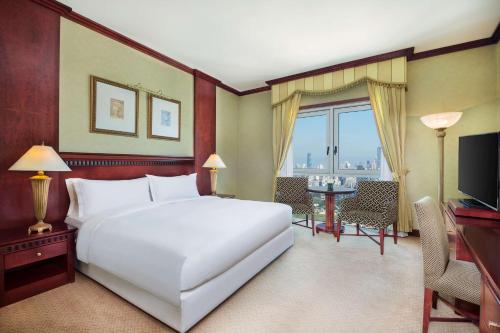 a bedroom with a large white bed and a television at Habtoor Metropolitan Palace Hotel in Beirut