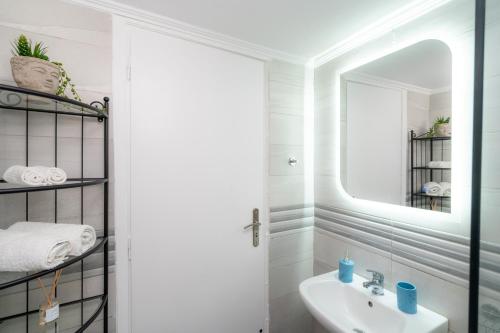 a white bathroom with a sink and a mirror at SyntheSeas Residence in Rethymno Town