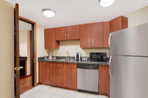 a kitchen with wooden cabinets and a stainless steel refrigerator at DoubleTree by Hilton Stamford in Stamford