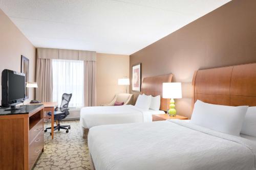 a hotel room with two beds and a television at Hilton Garden Inn Tuscaloosa in Tuscaloosa