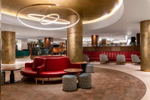 una hall con divano rosso, tavoli e lampadario a braccio di Hilton Birmingham Metropole Hotel a Bickenhill