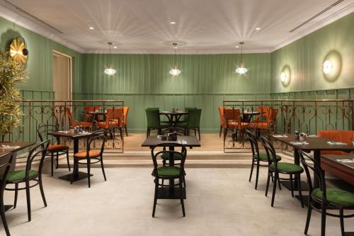 a restaurant with green walls and tables and chairs at Hilton Birmingham Metropole Hotel in Bickenhill