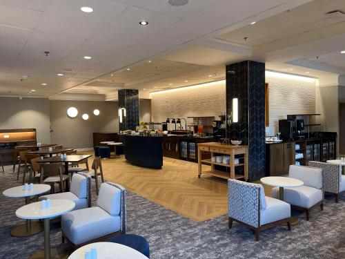 a lobby with tables and chairs and a cafeteria at Hilton Birmingham Metropole Hotel in Bickenhill