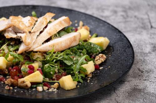 a black plate with a salad with chicken on top at Hilton Birmingham Metropole Hotel in Bickenhill