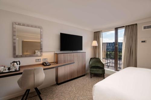 a hotel room with a bed and a desk and a television at Hilton Birmingham Metropole Hotel in Bickenhill
