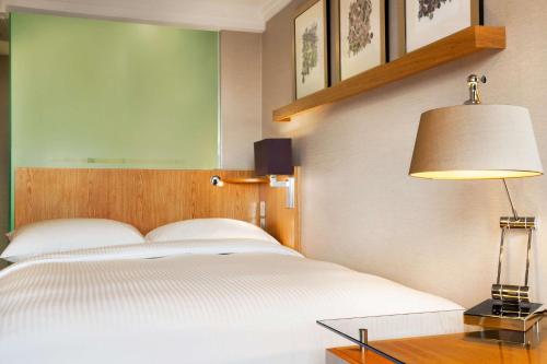 a bedroom with a white bed and a table with a lamp at Hilton Birmingham Metropole Hotel in Bickenhill