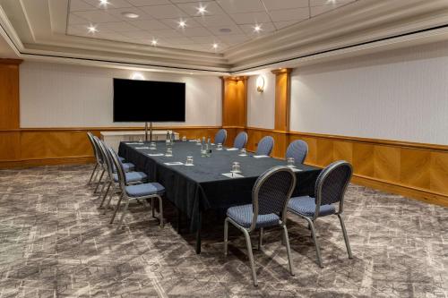 a conference room with a table and chairs and a screen at Hilton Birmingham Metropole Hotel in Bickenhill