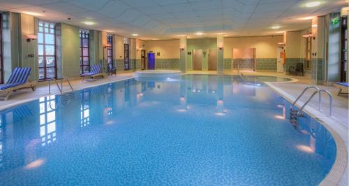 una gran piscina con sillas en una habitación de hotel en Hilton Puckrup Hall Hotel & Golf Club, Tewkesbury, en Gloucester