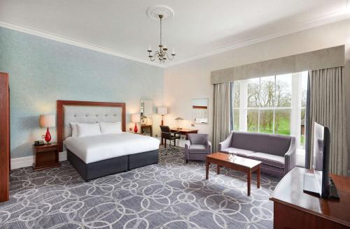 a hotel room with a bed and a living room at Hilton Puckrup Hall Hotel & Golf Club, Tewkesbury in Gloucester