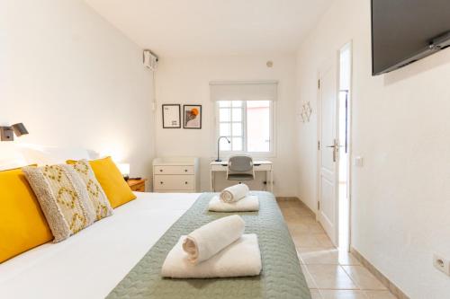 een slaapkamer met een groot wit bed met gele kussens bij Casa El Drago 6 in Breña Baja
