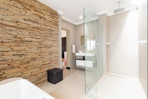 a bathroom with a stone wall and a glass shower at Laru home in Germiston