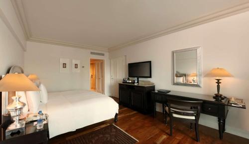 a bedroom with a bed and a desk and a television at Hilton Mumbai International Airport Hotel in Mumbai