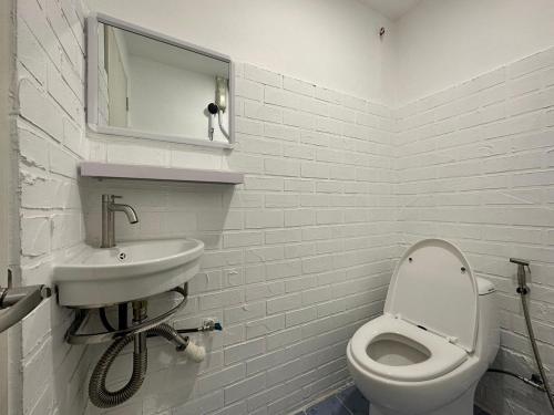 a white bathroom with a toilet and a sink at The White Den Sukhumvit 44 in Bangkok