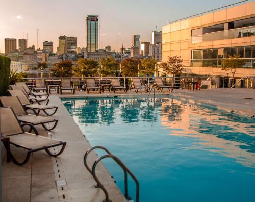a pool on the roof of a building with chairs at Hilton Buenos Aires in Buenos Aires