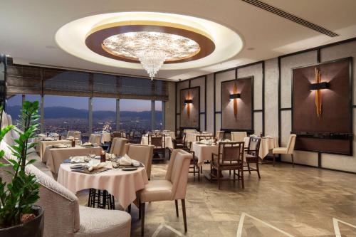 a dining room with tables and chairs and a chandelier at Hilton Bursa Convention Center & Spa in Bursa