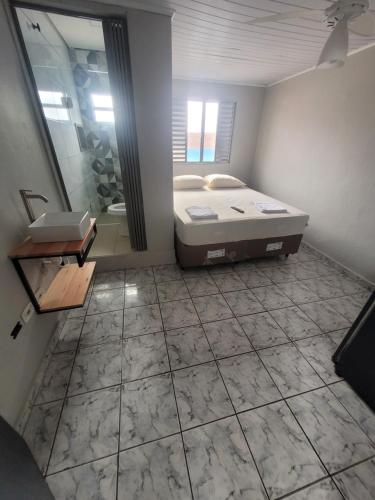 a bathroom with a bed and a shower and a sink at Pousada Aviação in Praia Grande