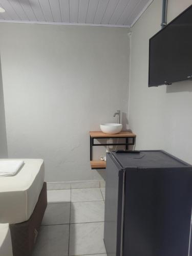 a bathroom with a television and a sink in it at Pousada Aviação in Praia Grande