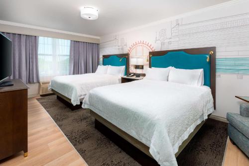 a hotel room with two beds and a flat screen tv at Hampton Inn Buffalo-Williamsville in Williamsville