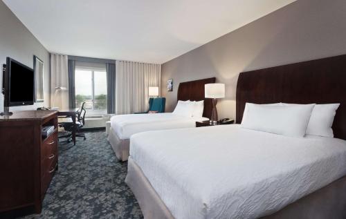 a hotel room with two beds and a desk and a television at Hilton Garden Inn Annapolis in Annapolis