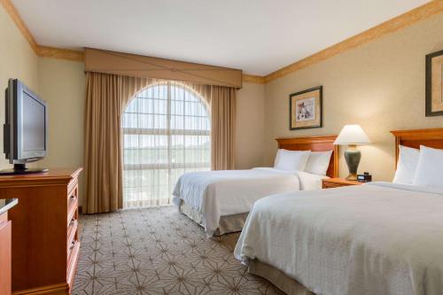 Embassy Suites by Hilton Columbia Greystone في كولومبيا: غرفة فندقية بسريرين وتلفزيون بشاشة مسطحة