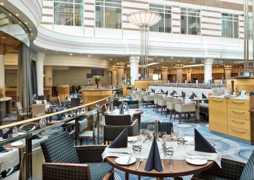 a restaurant with tables and chairs in a building at Hilton Paris Charles De Gaulle Airport in Roissy-en-France