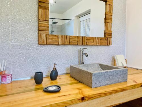 a bathroom with a stone sink on a wooden counter at Vanille, à proximité des plages, idéalement situé pour visiter la Guadeloupe in Le Gosier