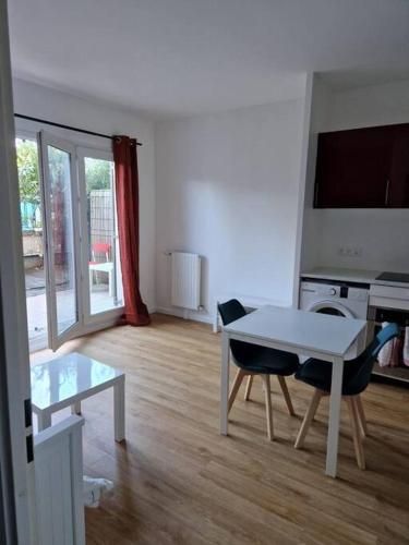 un salon avec une table et des chaises blanches dans l'établissement Appartement 20mn Paris Saint Lazare (4 personnes), à Argenteuil