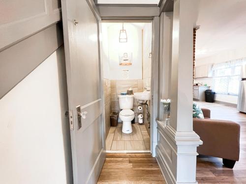 a hallway leading to a bathroom with a toilet at The Trotter Manor- With Private Yard & Free Parking, Minutes From Falls & Casino by Niagara Hospital in Niagara Falls