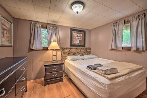 a bedroom with a bed and a dresser and windows at Wyatt Earp Cabin with Deck, 1 Mi to Raystown Lake! in Huntingdon
