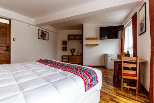 a bedroom with a large white bed and a kitchen at Hacienda del Valle Sagrado in Urubamba