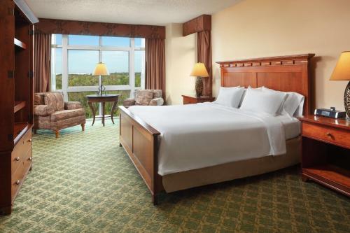 una habitación de hotel con una cama grande y una silla en Embassy Suites North Charleston Airport Hotel Convention, en Charleston