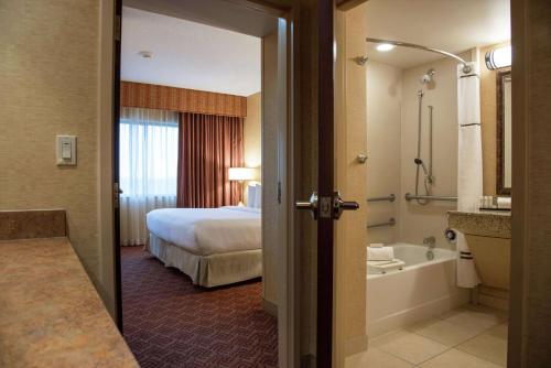 a hotel room with a bathroom with a bed and a tub at Embassy Suites by Hilton Charlotte Concord Golf Resort & Spa in Concord